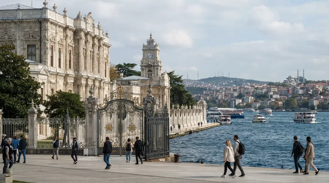 the ornate waterfront facade of Dolmabahçe Palace in daylight, with pale stone, carved detailing and the Bosphorus just beyond the gates