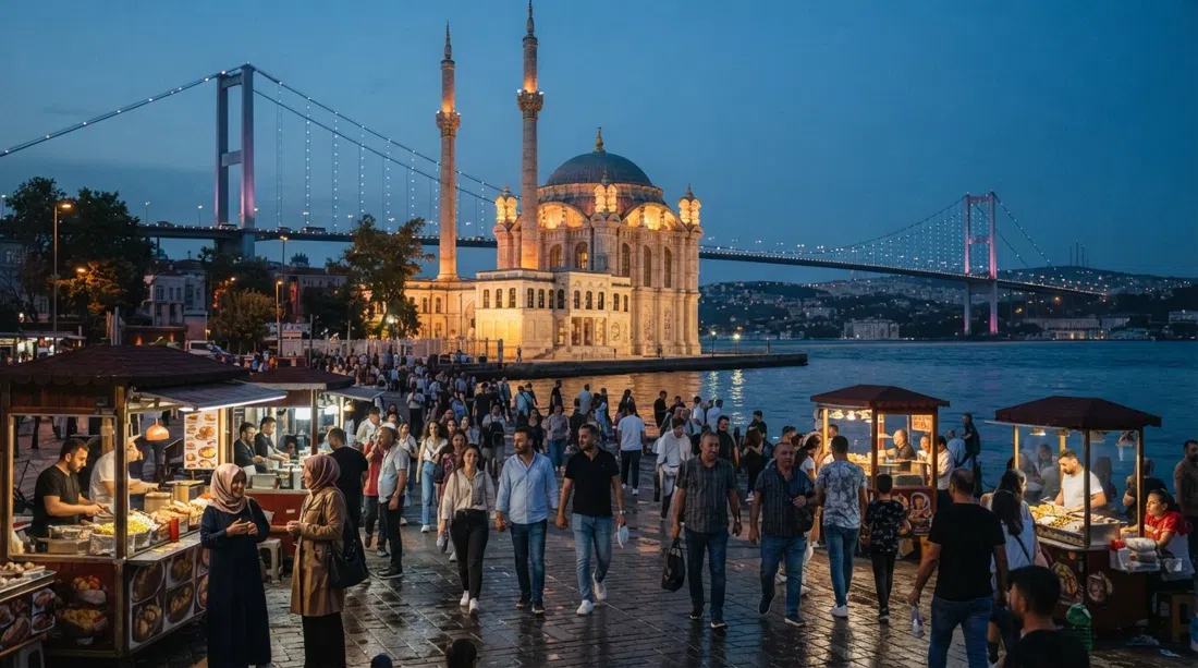 Mosquée d'Ortaköy et pont du Bosphore alignés derrière elle au crépuscule, la place en contrebas animée par les piétons et les étals de kumpir